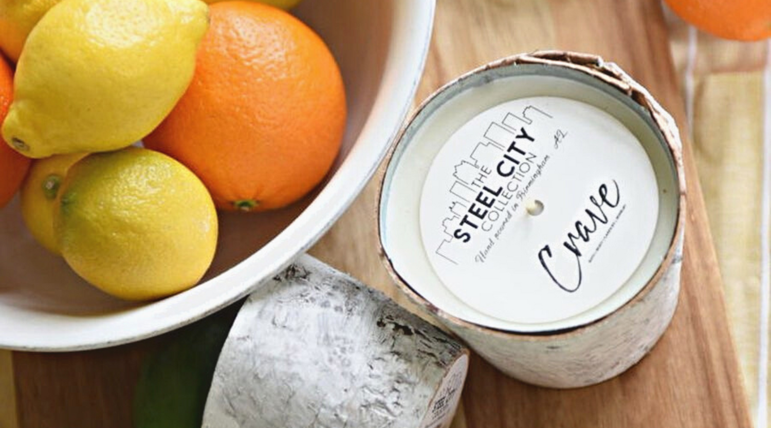 a steel city collection crave candle next to a bowl of oranges